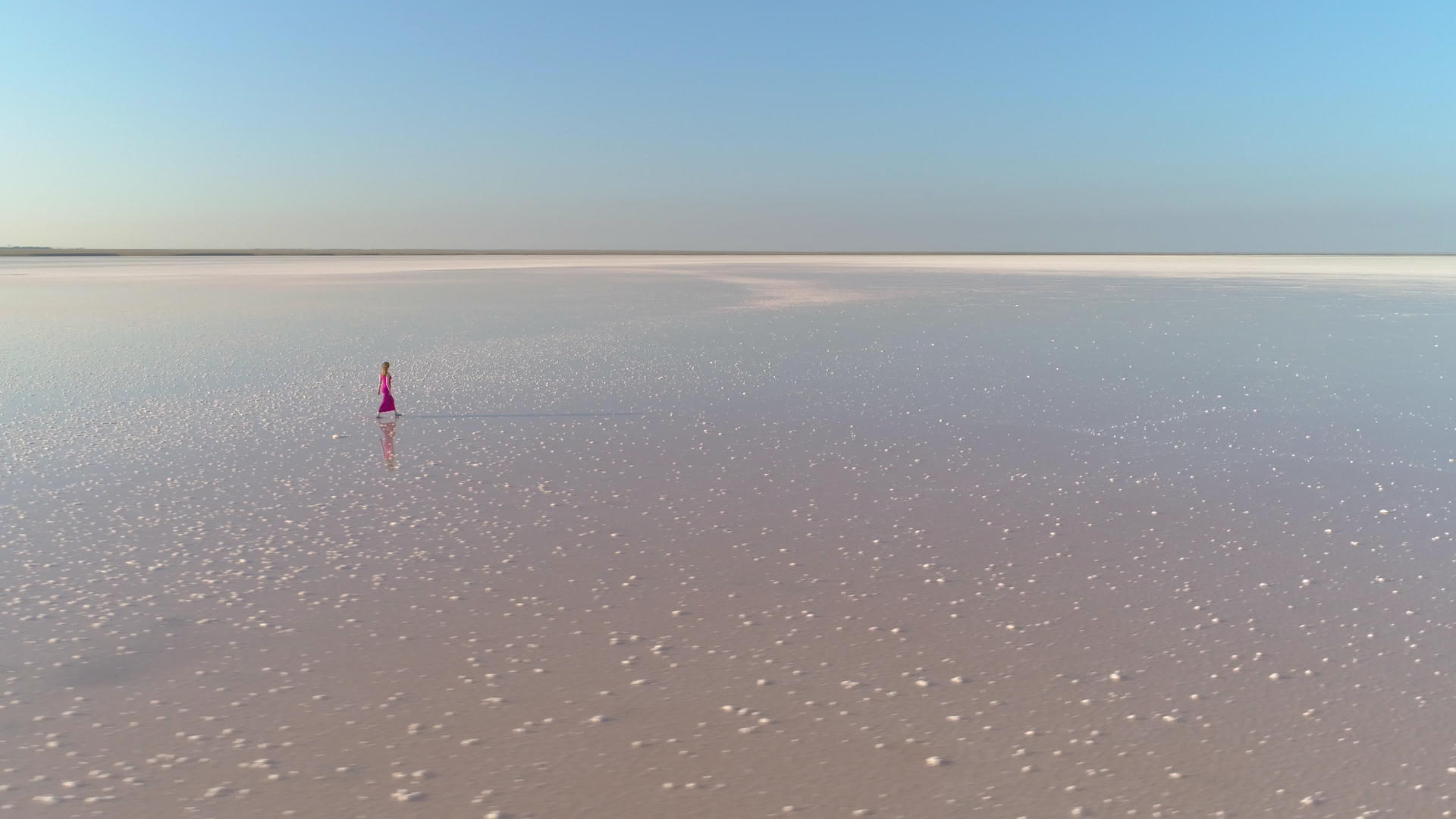 一个穿着红色长发裙子的孤独年轻女孩在巨大的盐湖上视频的预览图
