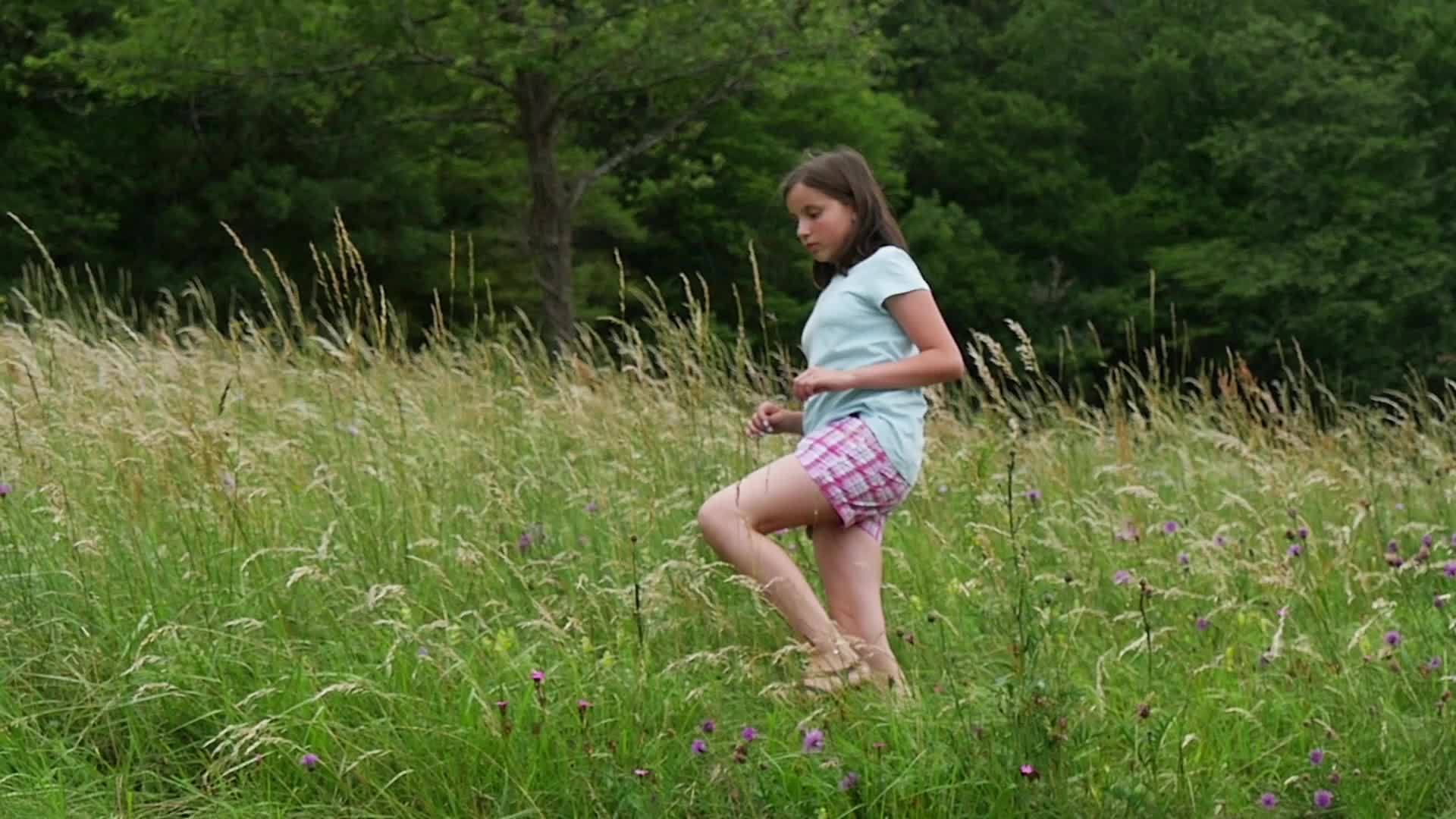 年轻女孩在高高的草地上慢慢地走着视频的预览图