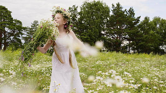 花圈里的女孩在盛开的田野里嗅着花束时尚模特视频的预览图