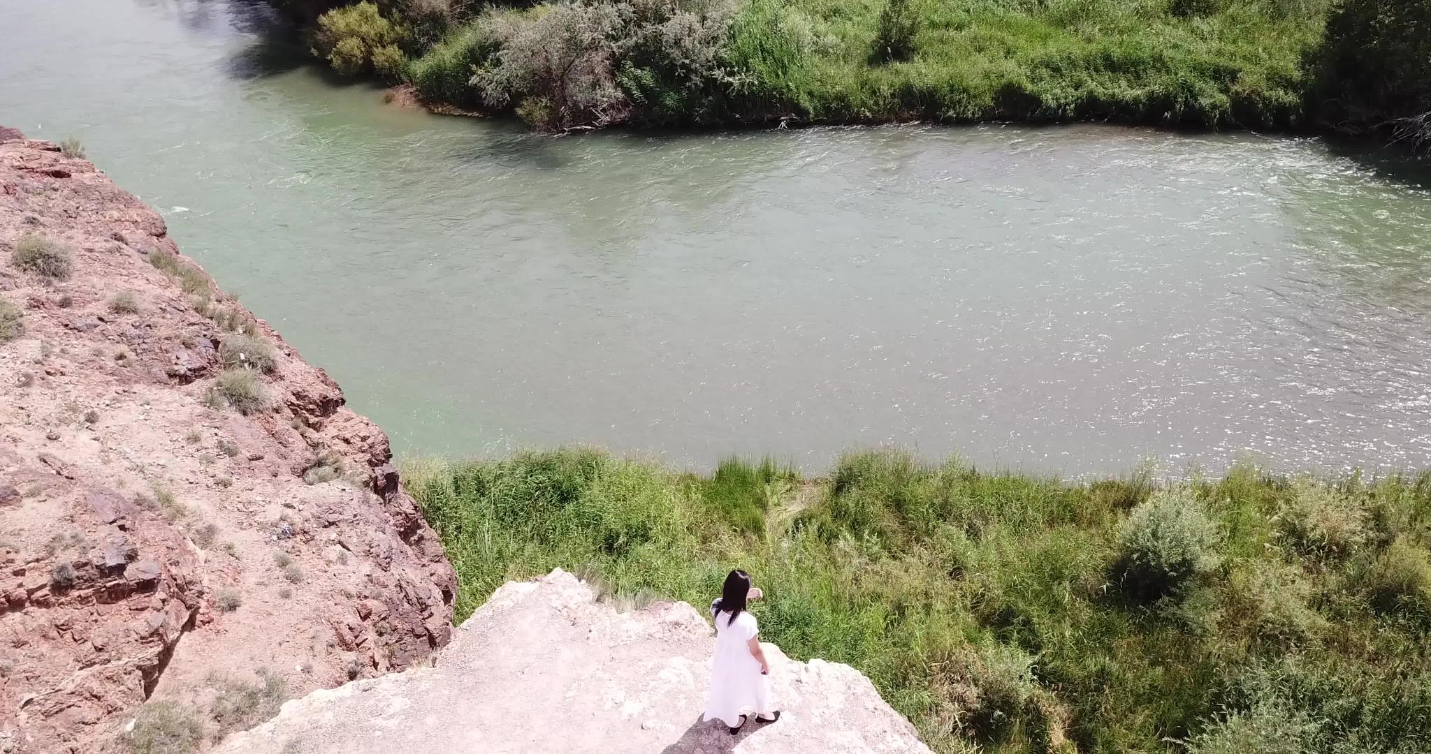 一个穿着白色衣服的年轻女孩看着峡谷风景视频的预览图