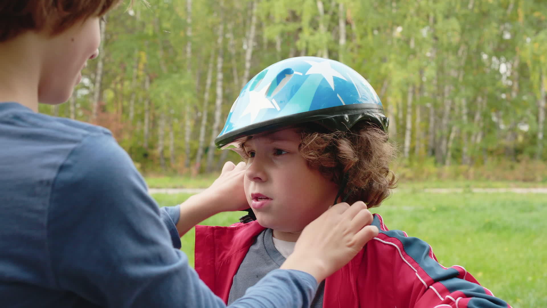 哥哥在夏天把自行车头盔戴在哥哥头上哥哥帮助小男孩视频的预览图