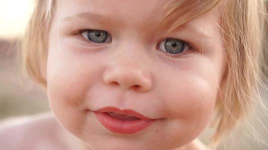 关上美丽一岁的金发女孩蓝眼睛微笑着夏天在海滩上视频的预览图
