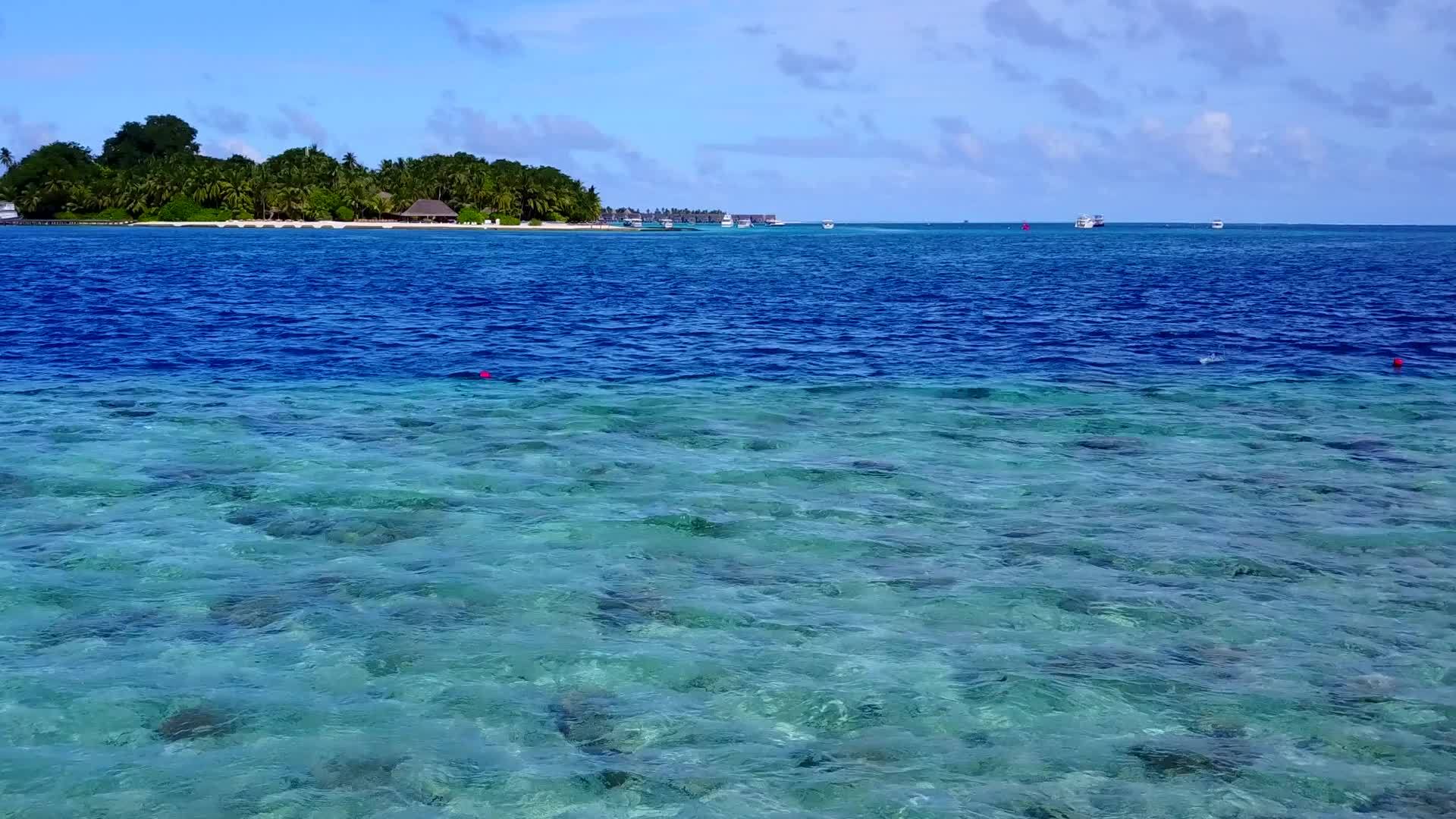 热带海滨海滩沿着蓝绿海航行珊瑚礁附近有一个干净的海滩背景视频的预览图