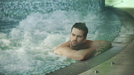 英俊的男人在按摩浴池里休息性感的男人在冬瓜浴池里放松视频的预览图