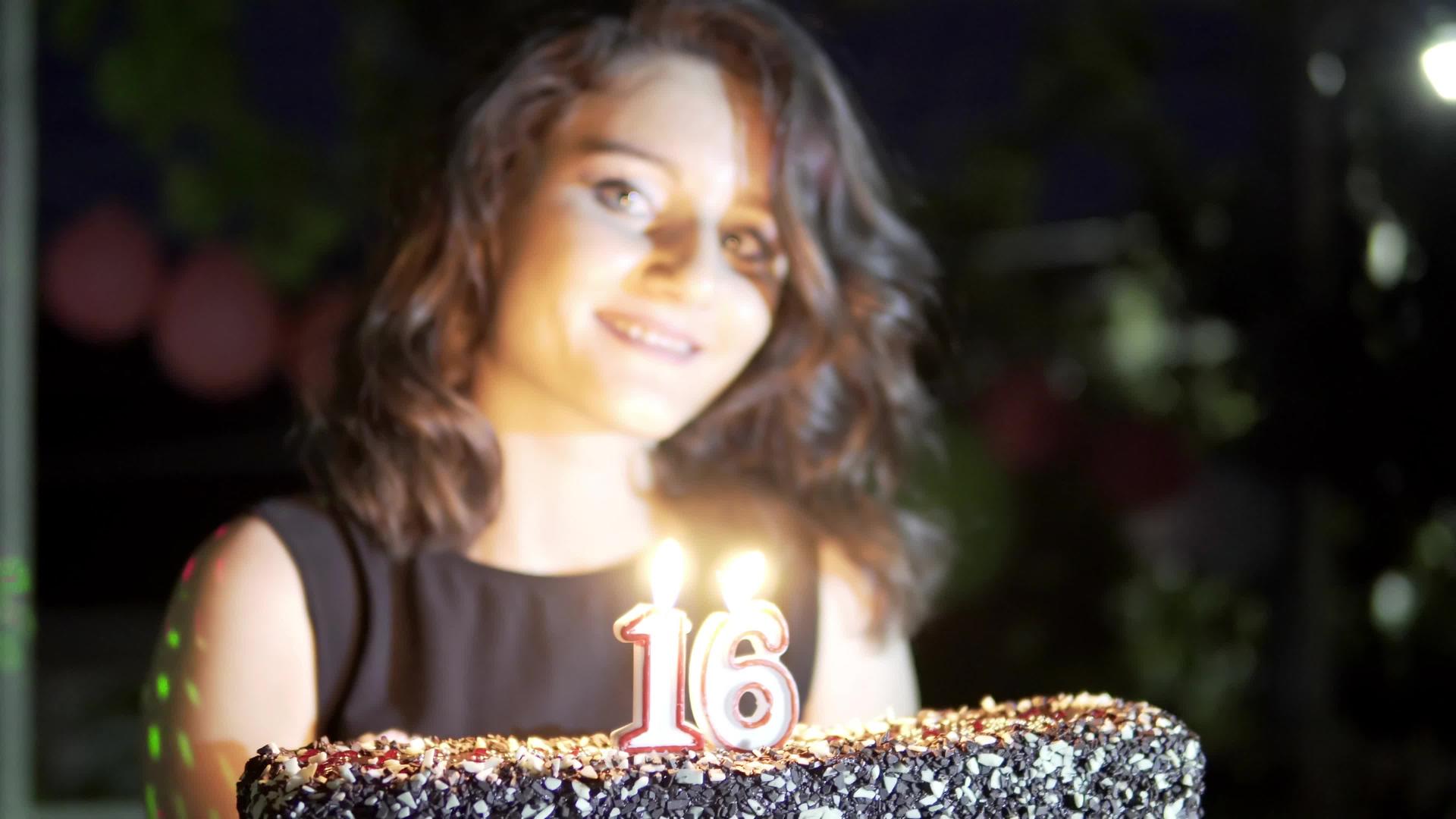 一个16岁生日派对的年轻女孩拿着蛋糕和蜡烛笑得很开心视频的预览图