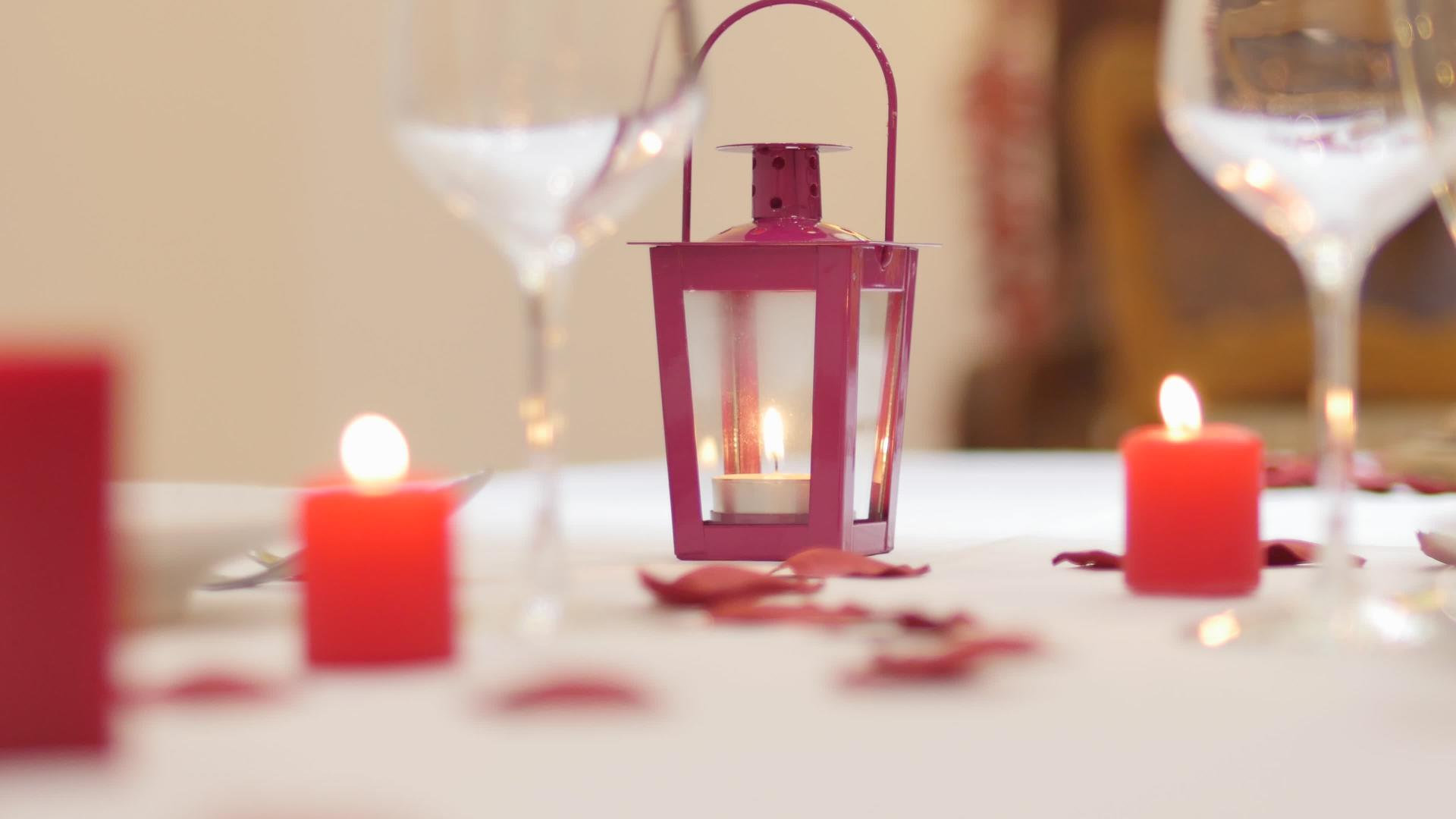 服务员把可爱的蜡烛放在桌上桌上有玫瑰花瓣、酒杯和瓷器视频的预览图