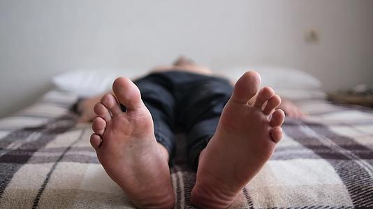 腿部特写男人仰面躺着选择性焦点抓挠脚扭动脚趾视频的预览图