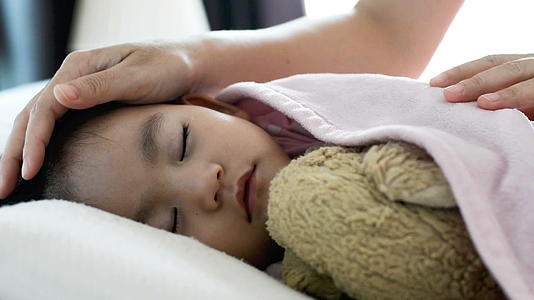 睡在床上母亲把毯子放在婴儿的肚子里有一条毯子视频的预览图