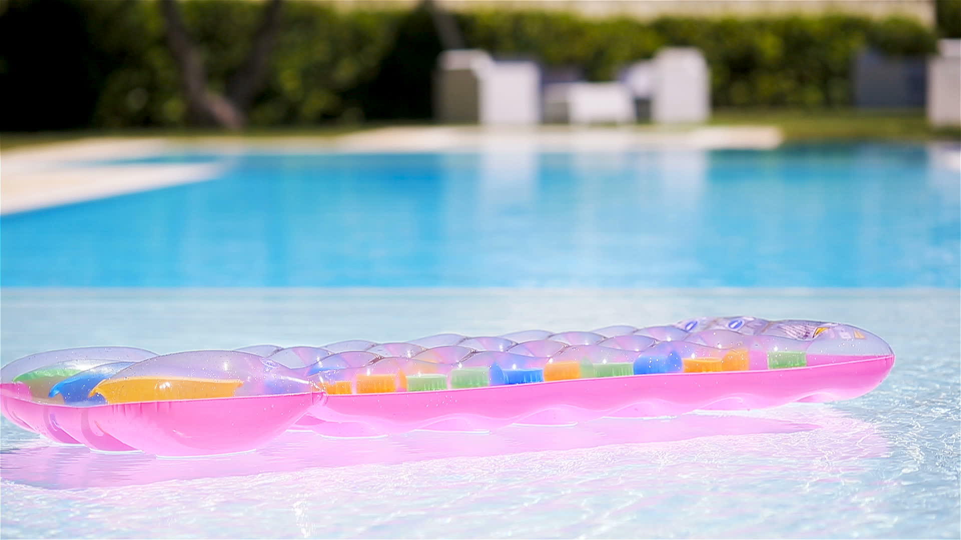 漂浮在游泳池水面上的粉色可充气床垫视频的预览图