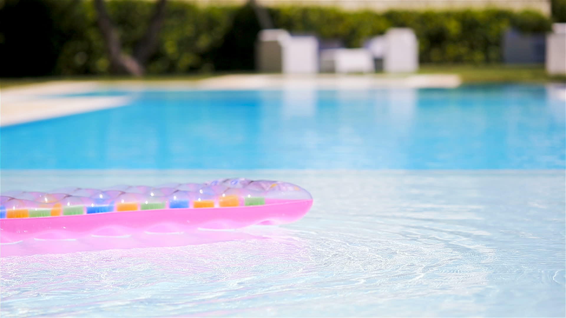 粉色可充气床垫漂浮在游泳池的水面上视频的预览图