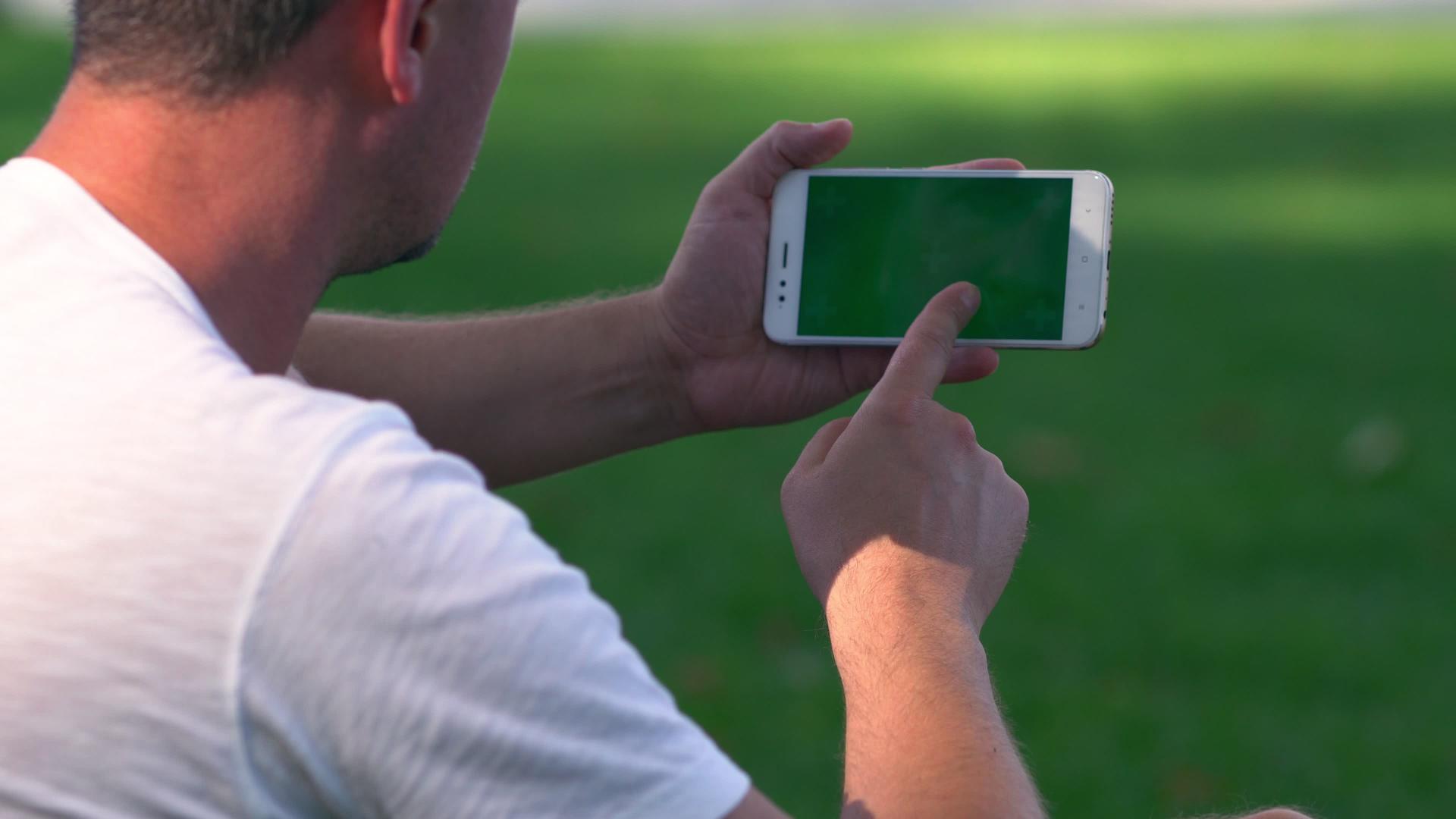 坐在户外的男人在手机上滚动视频的预览图