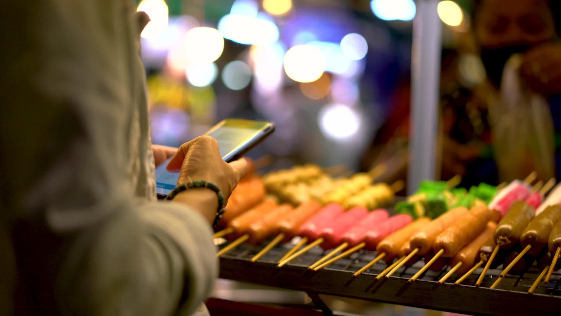 女性使用智能手机支付Asia街头食品费用视频的预览图