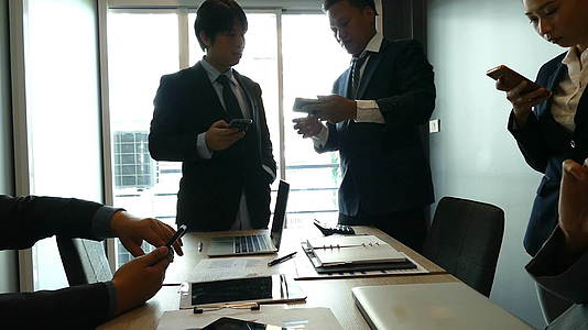 一群商人和女商人在办公室里使用智能手机和应用程序视频的预览图