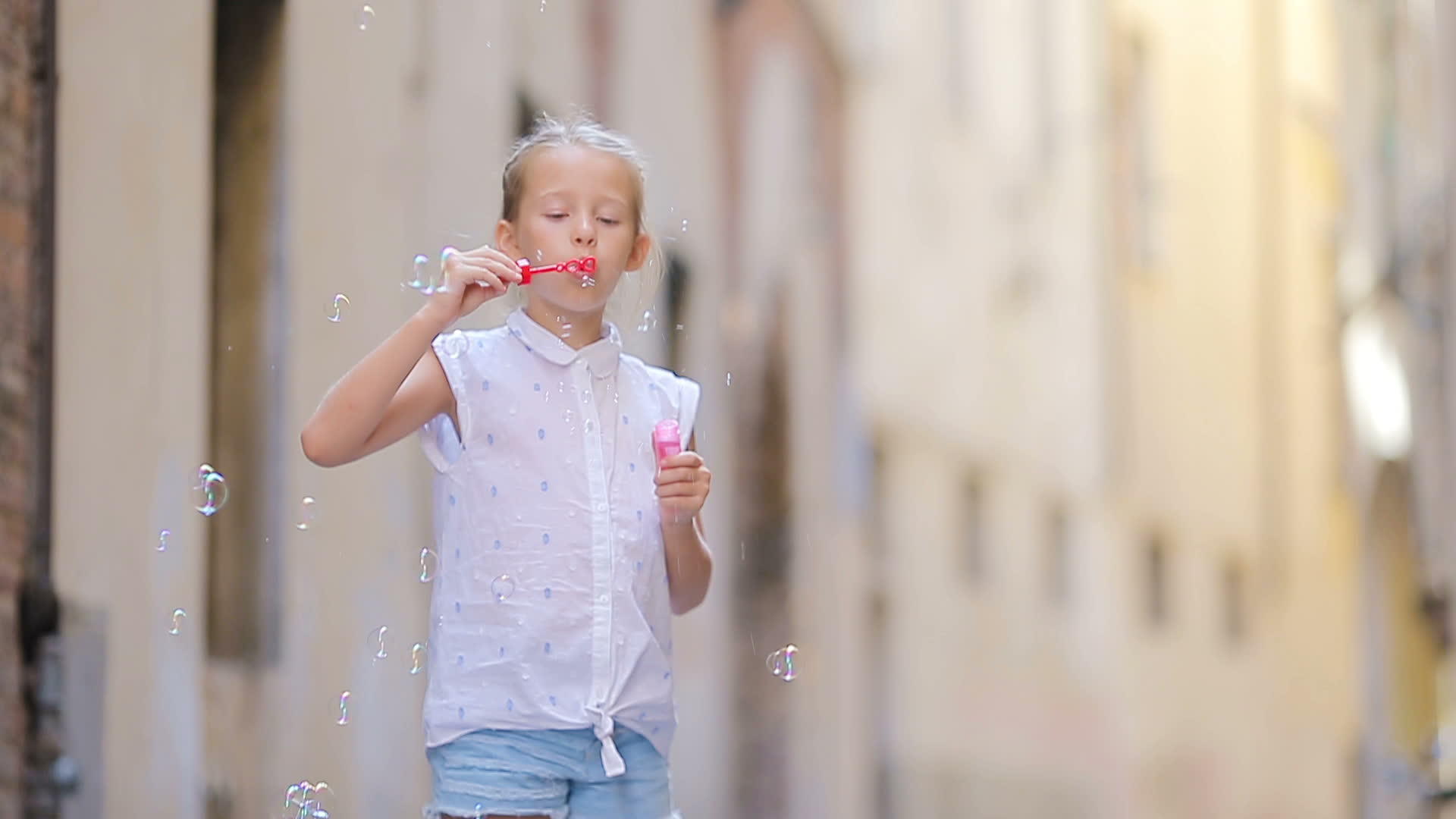 这个可爱的小女孩在户外吹着欧洲城市的肥皂泡沫在罗马享受着视频的预览图