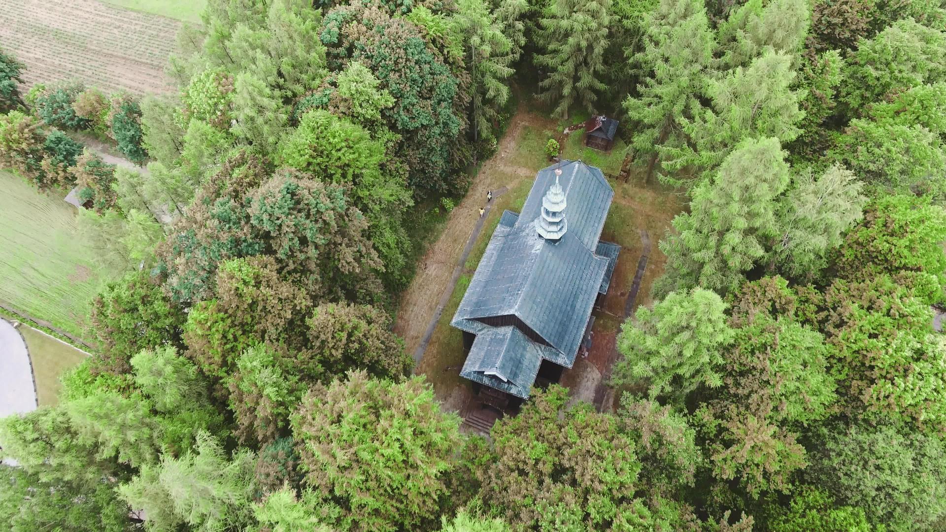 无人机在小城市的木制教堂草地之间录制视频的预览图