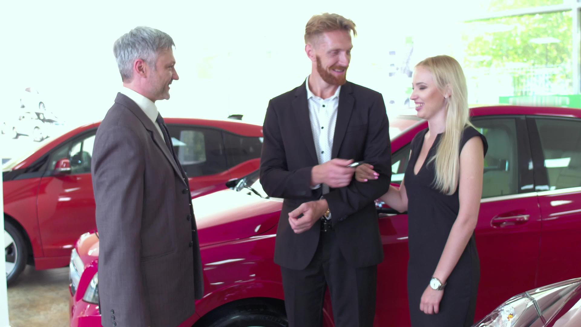 汽车经销商把钥匙从新车传递给快乐的年轻夫妇视频的预览图