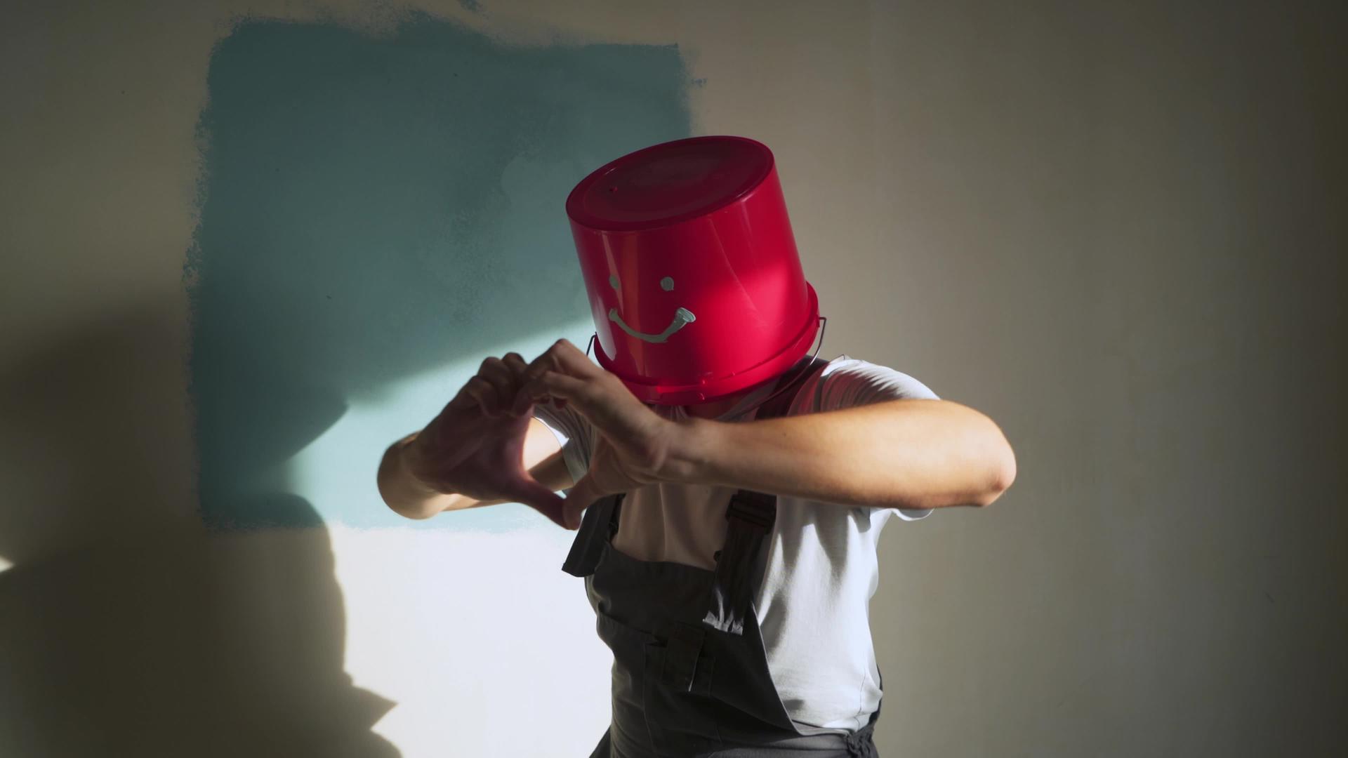 穿着制服的工人头上戴着红色的水桶开心地跳舞视频的预览图