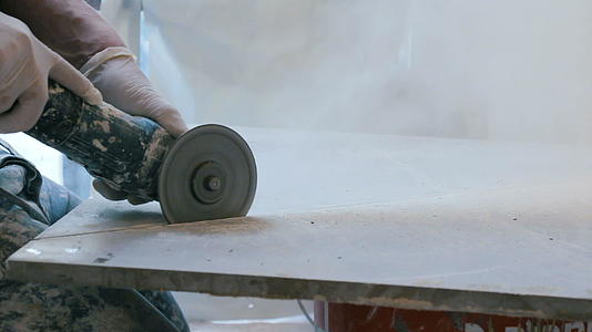 在施工现场使用角磨机切割瓷砖的工人视频的预览图
