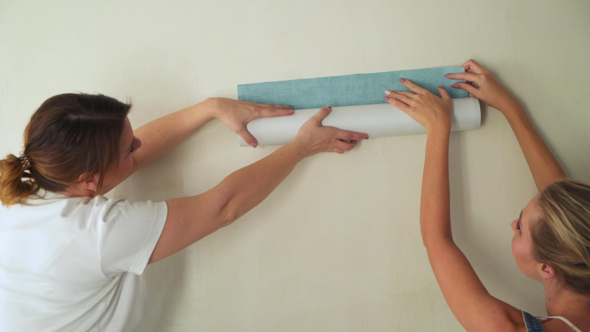 建筑工地上的两个女孩在墙上粘上了墙纸视频的预览图