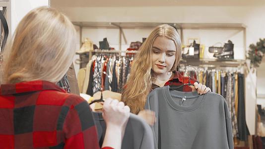 年轻女子在时装店的镜子前检查衣服视频的预览图