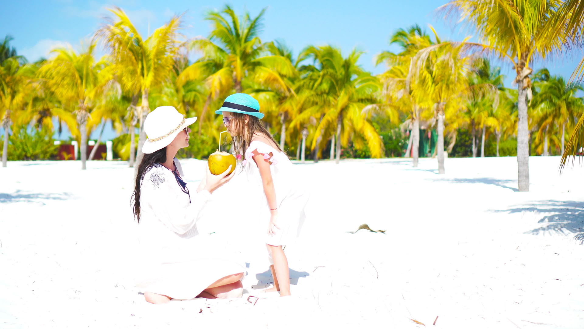 孩子和年轻的母亲在异国情调的海滩上喝椰奶可爱的女孩视频的预览图