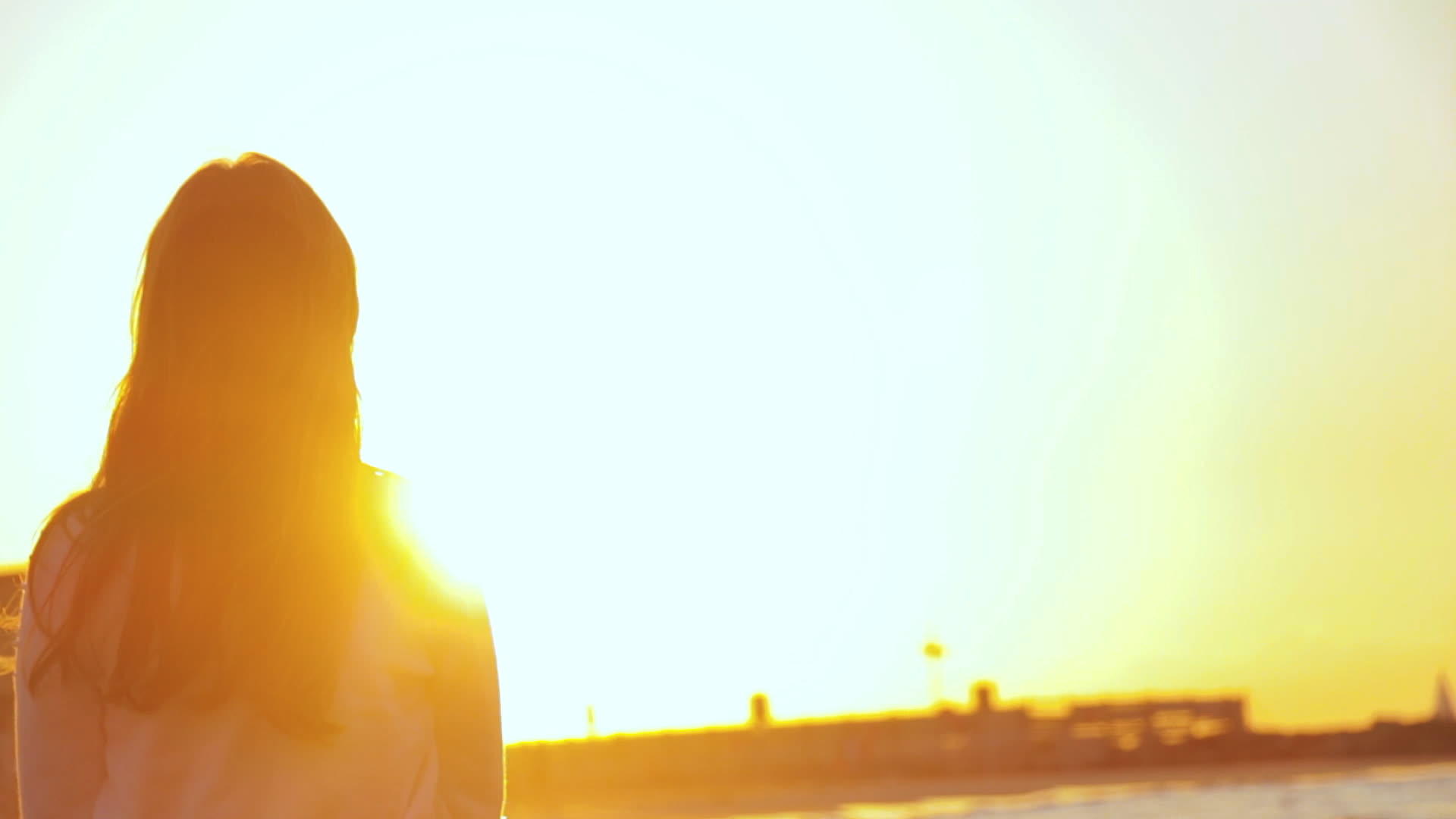 一个无忧无虑、无法辨认的女孩在背后享受着美丽而奇特的日落视频的预览图