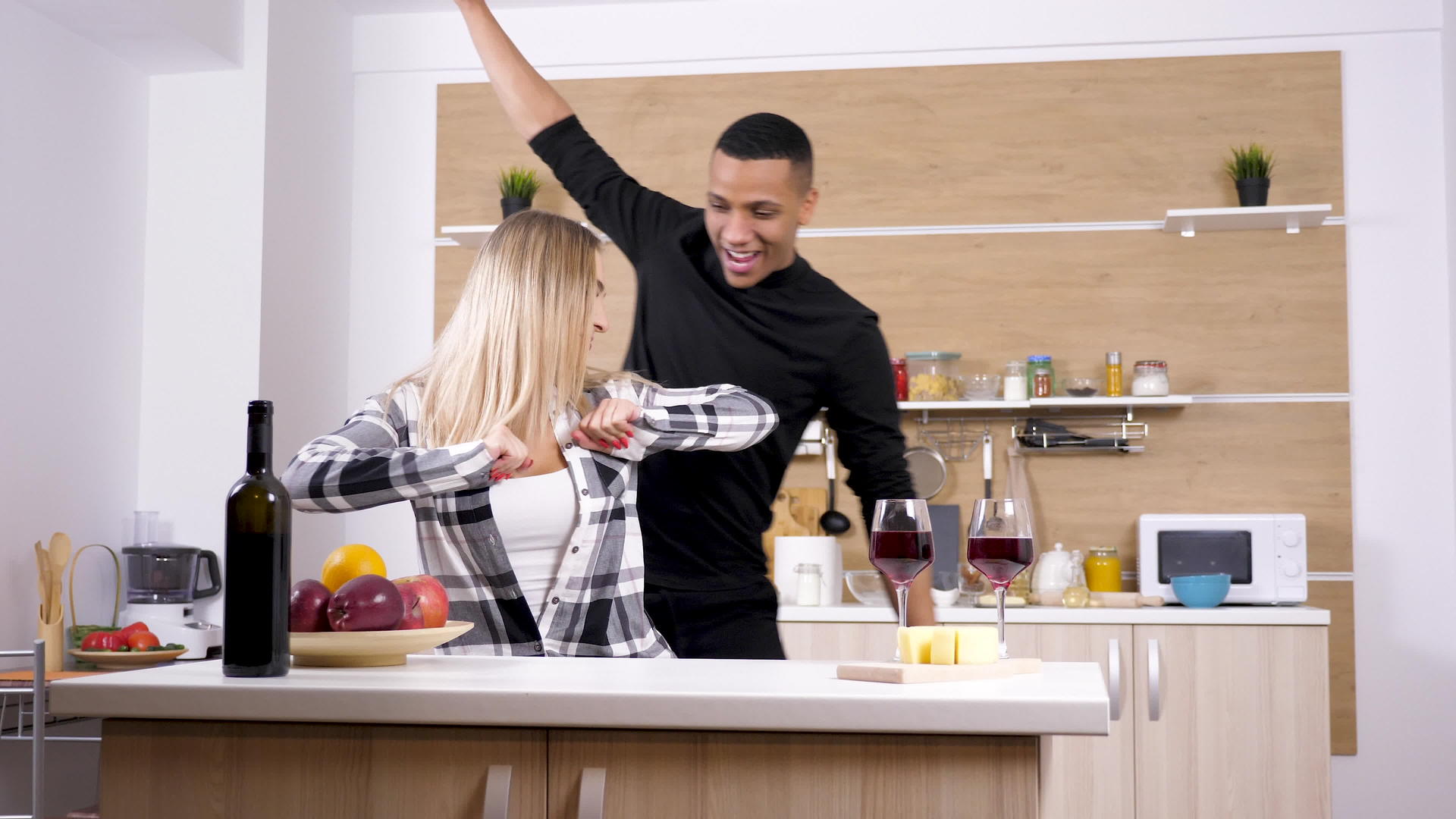 美丽的跨种族年轻夫妇在厨房里跳舞、大笑和玩得开心视频的预览图