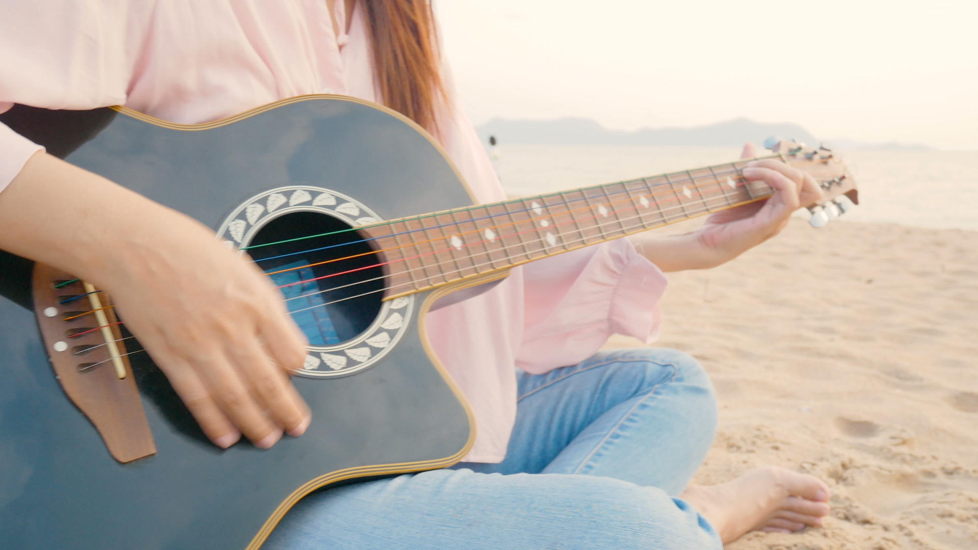4k关闭长发女孩的长发女孩在海滩上弹奏吉他日落时温柔的感觉视频的预览图