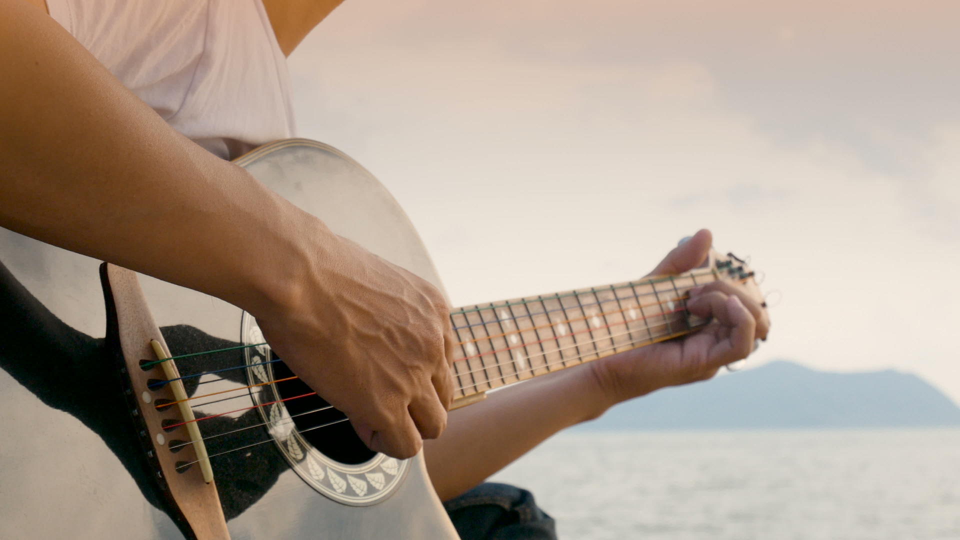 日落时在沙滩上弹吉他的人感觉很放松视频的预览图