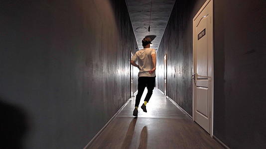 当代年轻男性嬉皮舞者在长长的黑暗走廊里视频的预览图