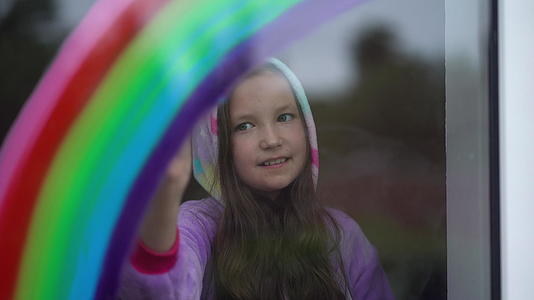 穿着睡衣的女孩在家里的窗户上画了彩虹她喜欢吃晚饭视频的预览图