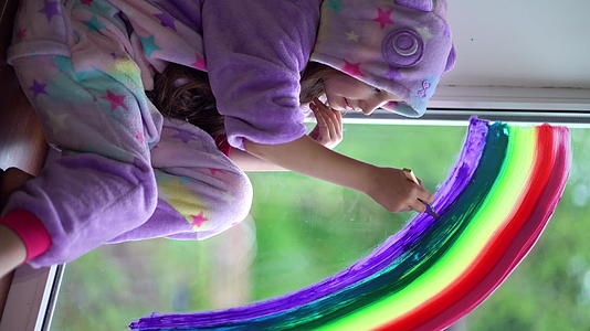 穿着睡衣的女学生在家里的窗户上画了彩虹留在家里视频的预览图