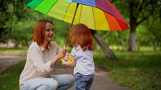 母亲和女儿站在彩虹伞下视频的预览图