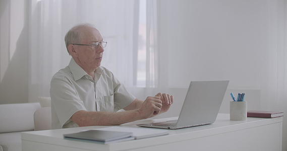 老年男性律师使用带有网络相机的笔记本电脑通过互联网咨询客户视频的预览图