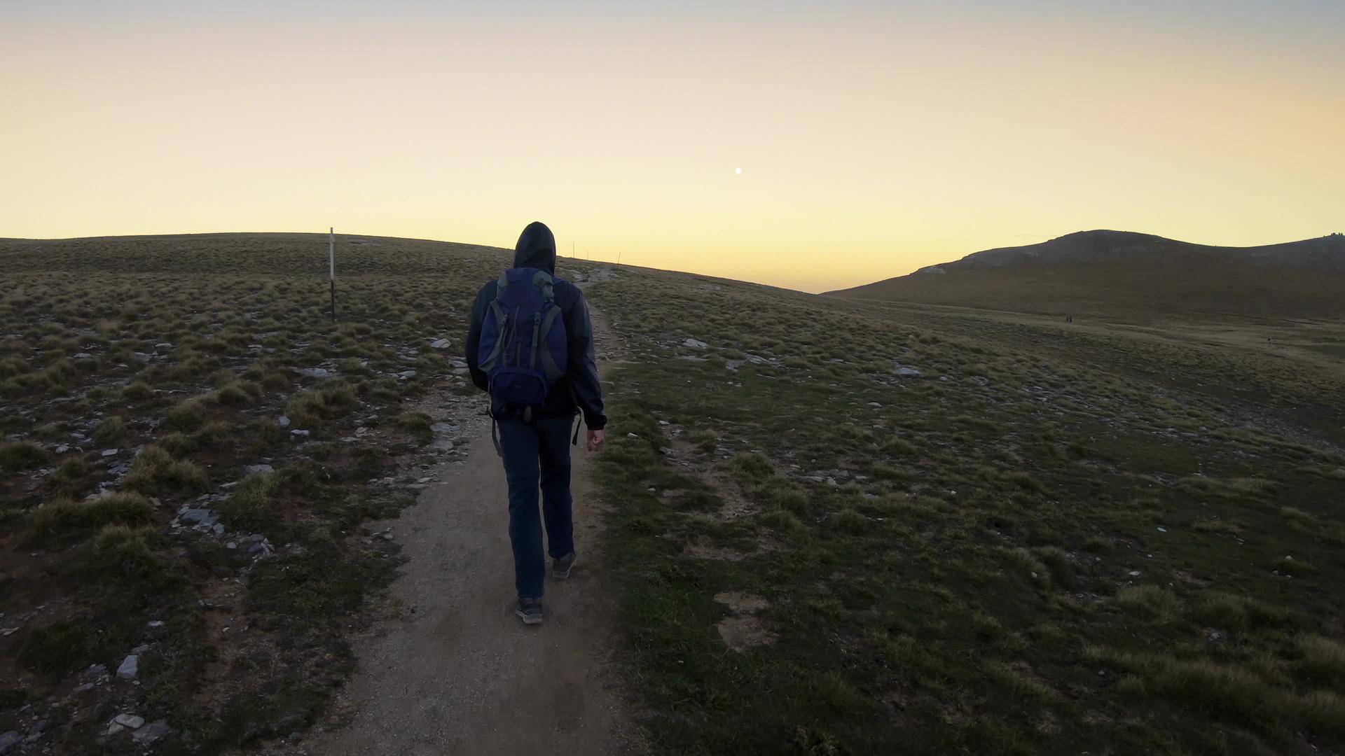背着背包的徒步旅行者在奥林波斯登山后日落时走在山脚下视频的预览图