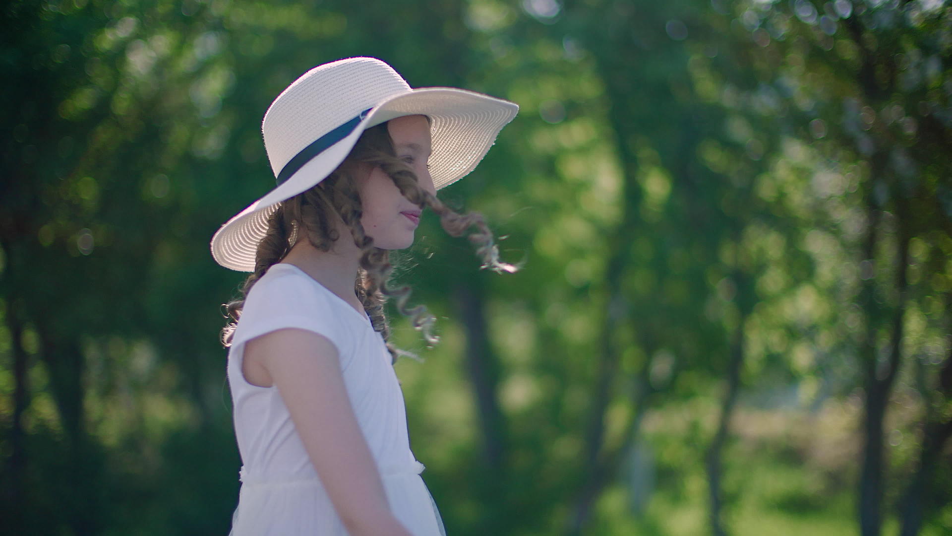微笑的女孩和卷发、帽子在阳光明媚的日子里视频的预览图