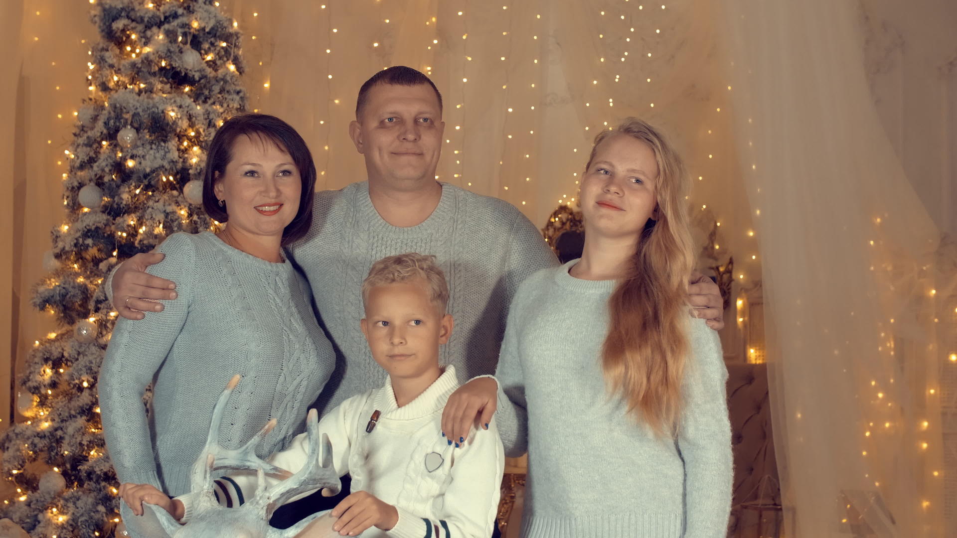 站在舒适的客厅里家庭在圣诞树的背景下微笑视频的预览图