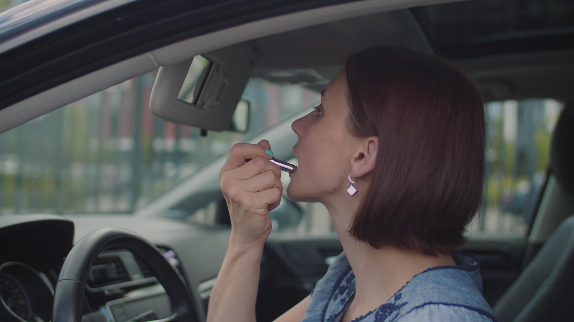 一名30岁的年轻女子坐在车里涂口红而女司机的侧面在车上视频的预览图