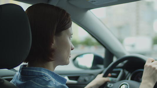 30岁的年轻女性在城市驾驶汽车女司机穿着方向盘视频的预览图
