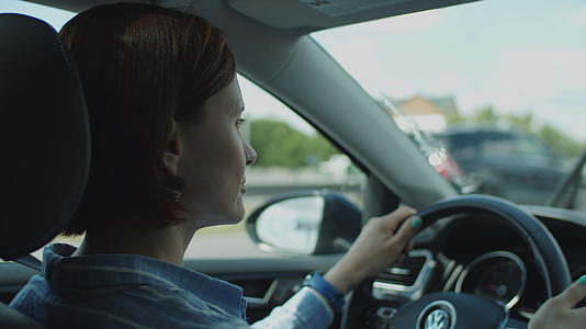 30岁的年轻女性在城市驾驶汽车女司机穿着方向盘视频的预览图