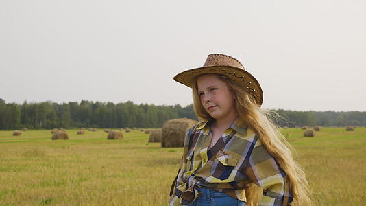 在干草堆背景的农村地区年轻的奶牛女孩戴着帽子视频的预览图