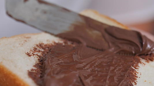 在一块面包上撒上巧克力奶油视频的预览图