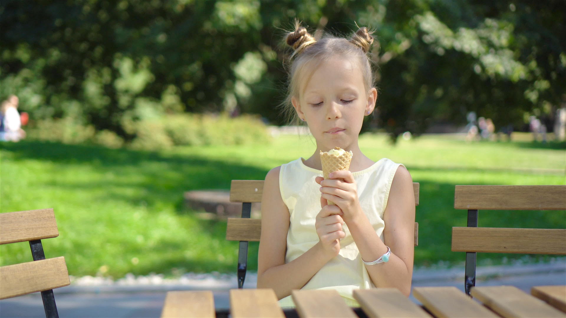 可爱的小女孩在夏天在户外咖啡馆吃冰淇淋享受真正的孩子视频的预览图