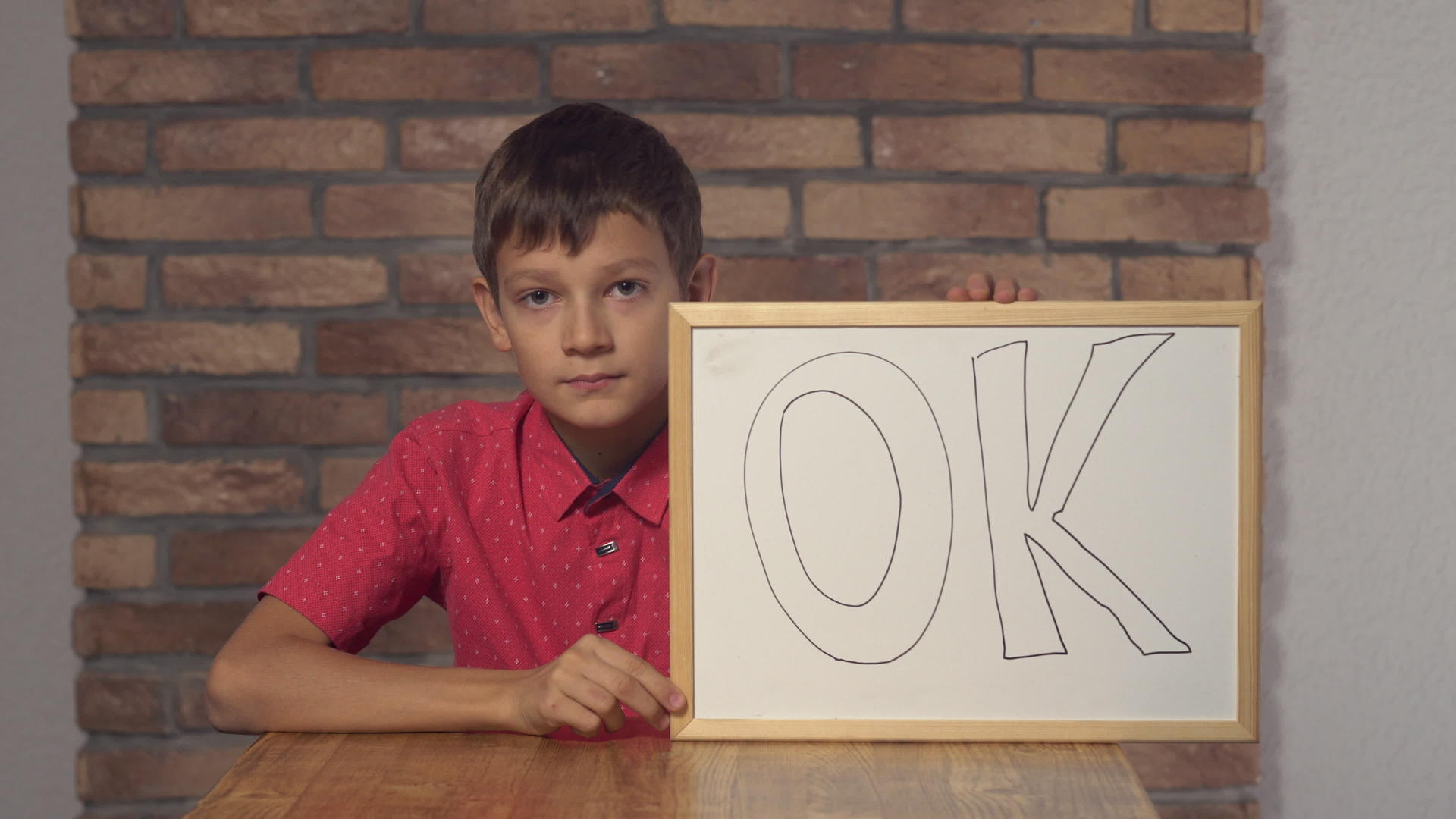 坐在桌子上的孩子写着OK视频的预览图