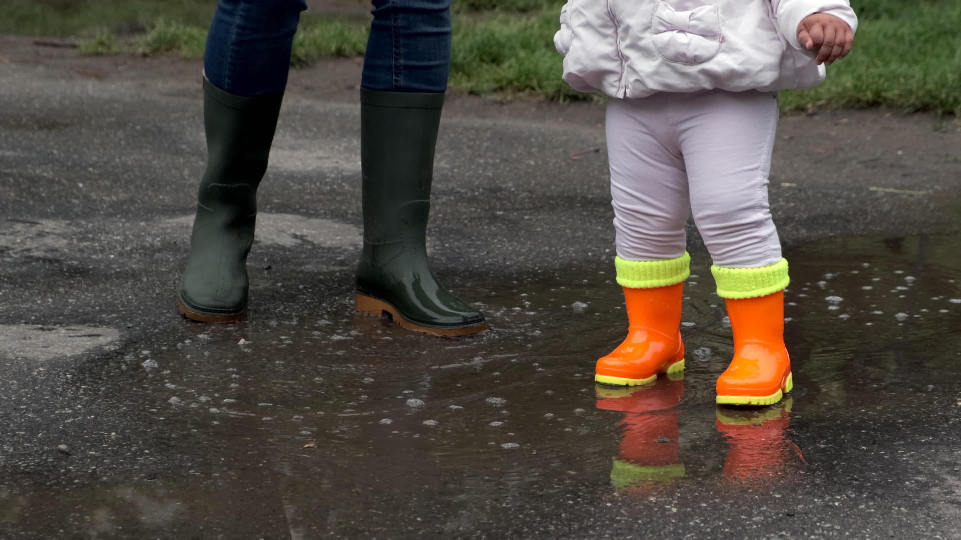 儿童橡胶橙色靴子和母亲的绿色靴子视频的预览图
