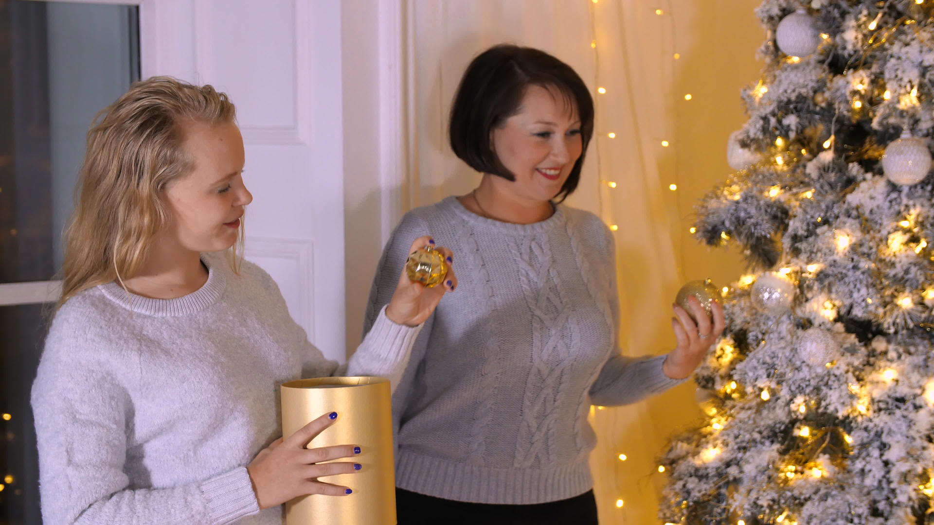母亲和母亲在圣诞前夕在客厅装饰圣诞树视频的预览图