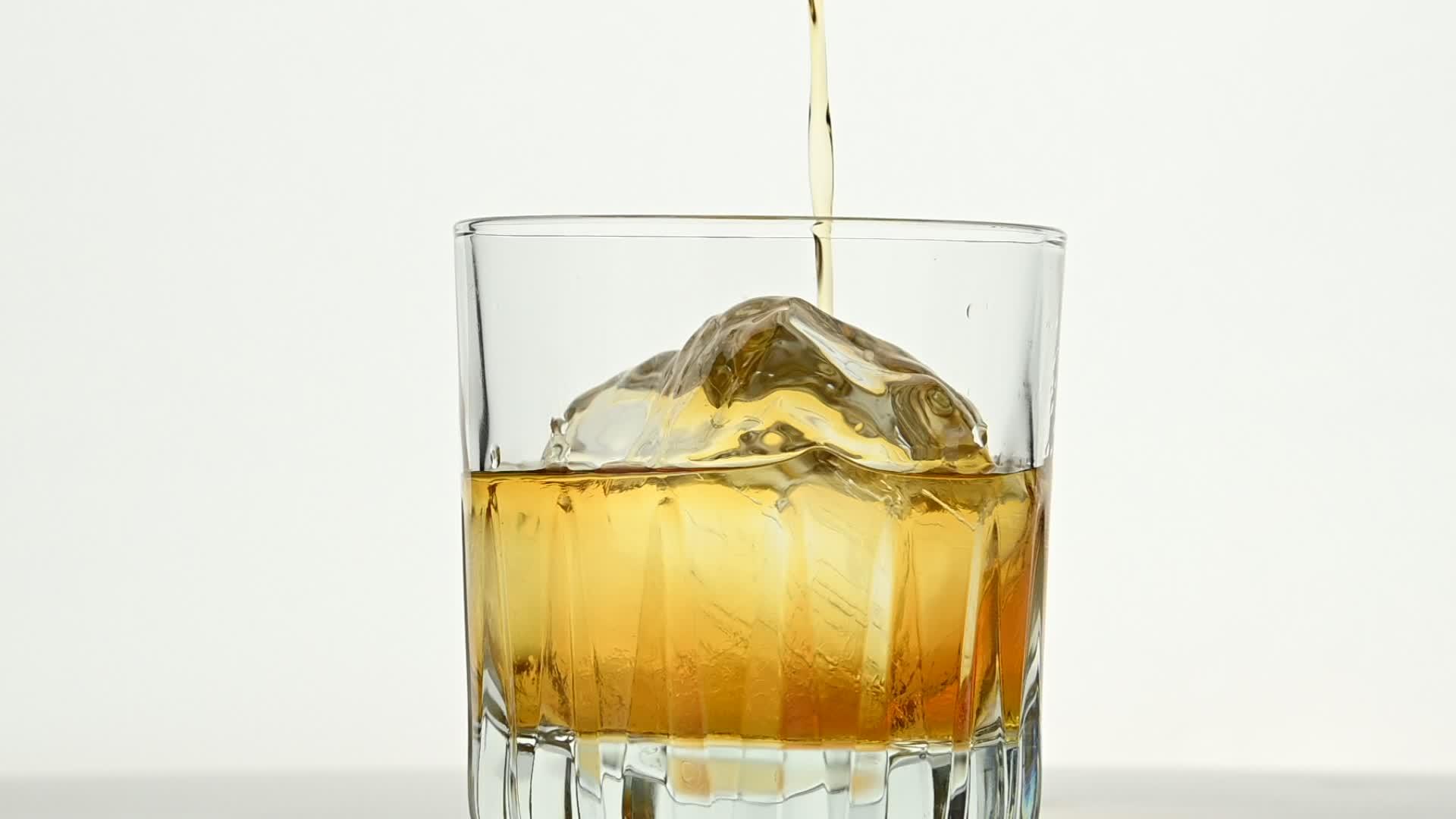 把威士忌倒在冰岩上的白色玻璃上视频的预览图