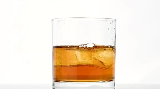 威士忌杯里的冰雪立方体旋转在白色之上视频的预览图