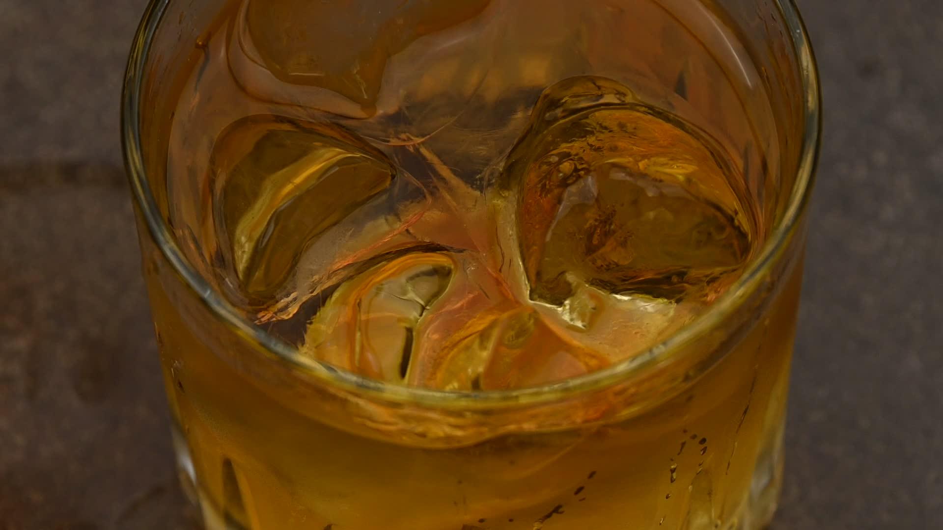 冰雪立方体在桌上的威士忌杯中旋转视频的预览图