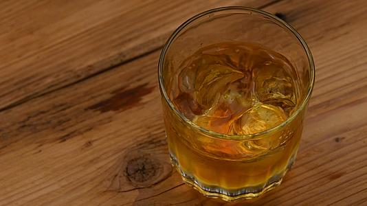冰落在酒吧柜台的威士忌杯里视频的预览图